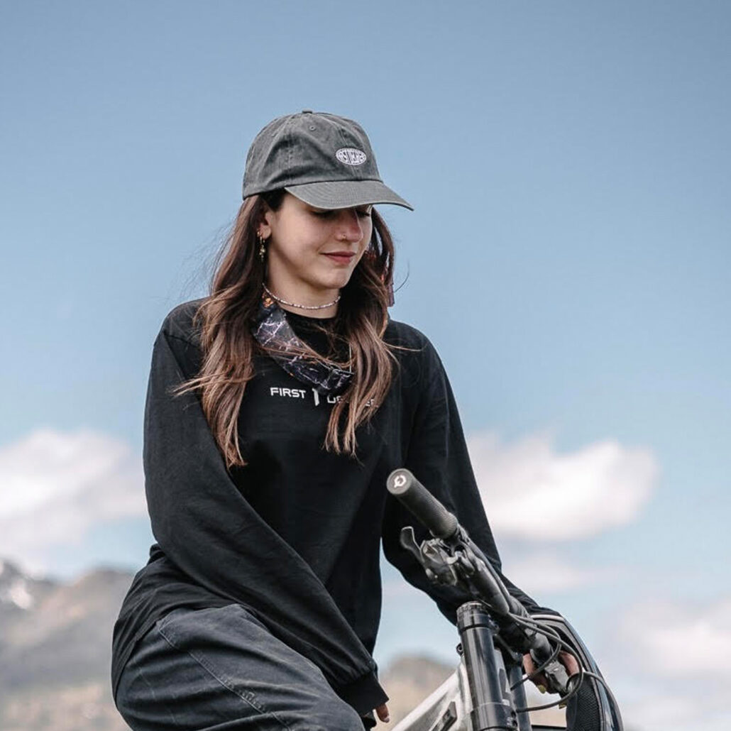 Frau trägt FIRST DEGREE Dad Hat in Washed Grey auf einem Mountainbike